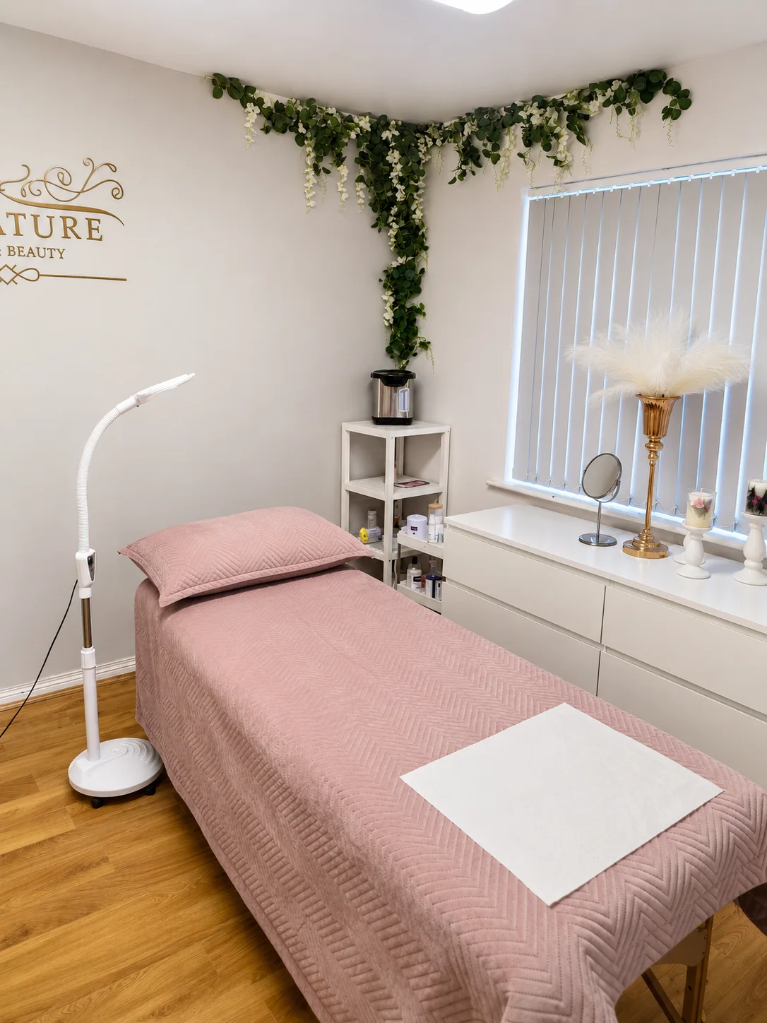 Pink treatment bed beside a window and leafy wall decorations